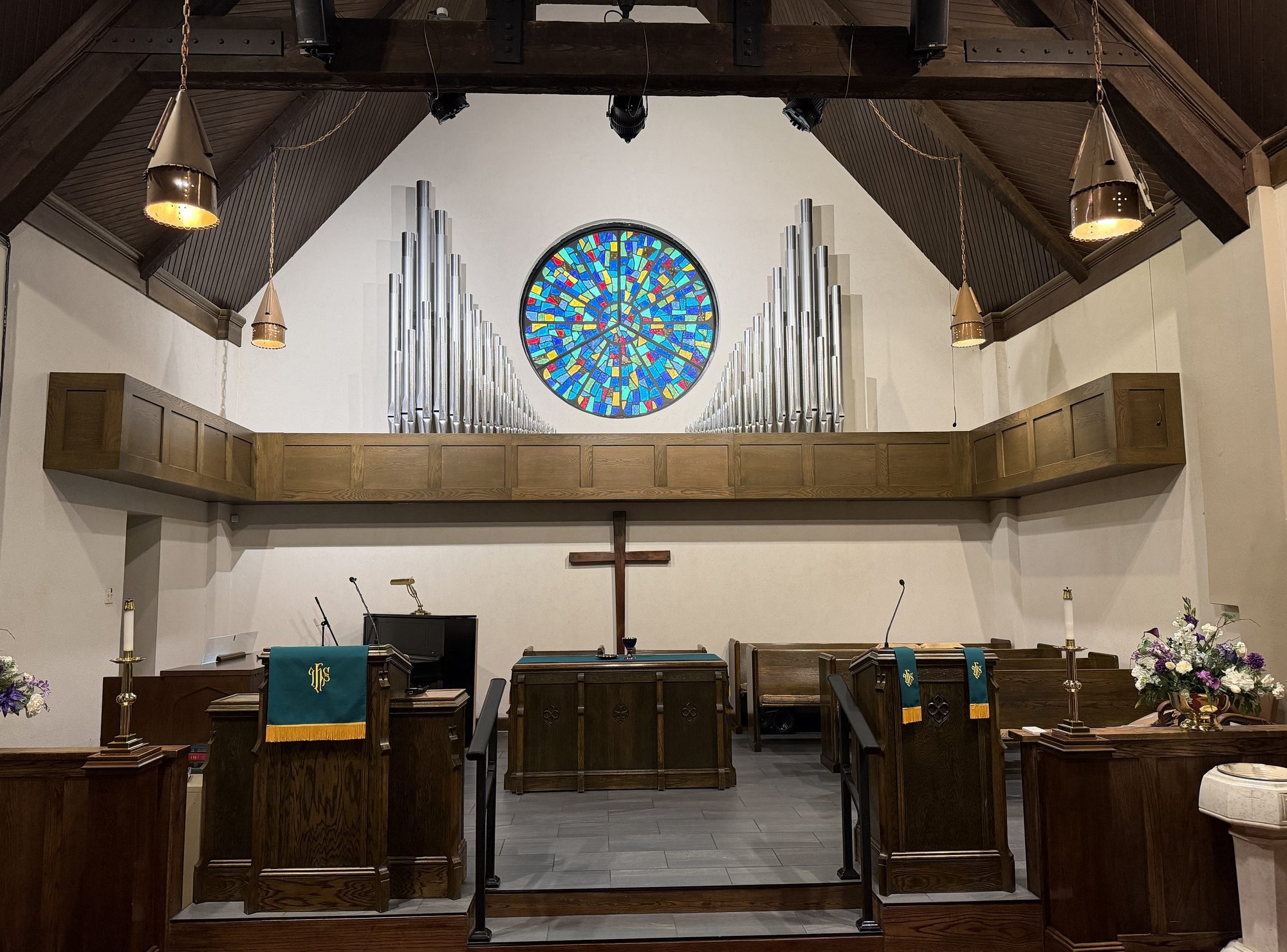 Organ pipes and a round stained-glass window above a chancel